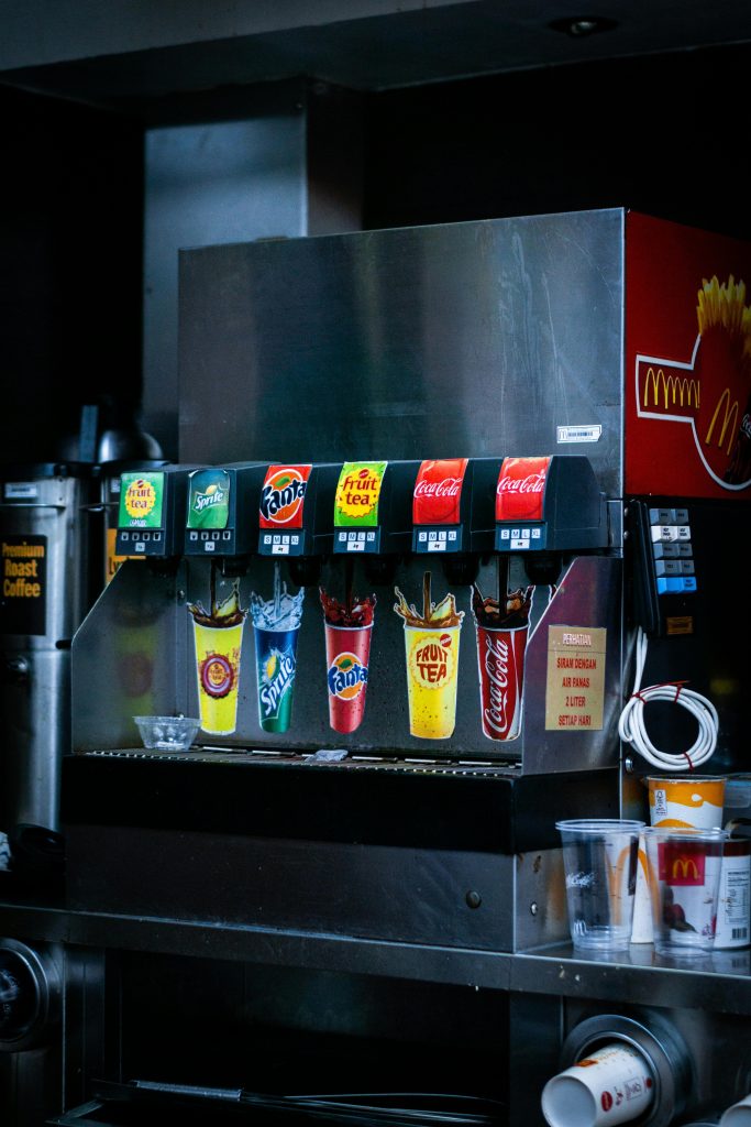 Soft drink dispenser with various soda options in fast food restaurant.