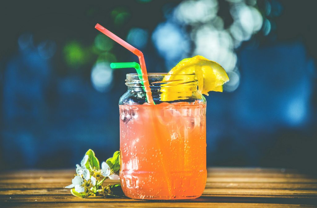 Refreshing summer citrus cocktail served in a mason jar with lemon slices and straws.