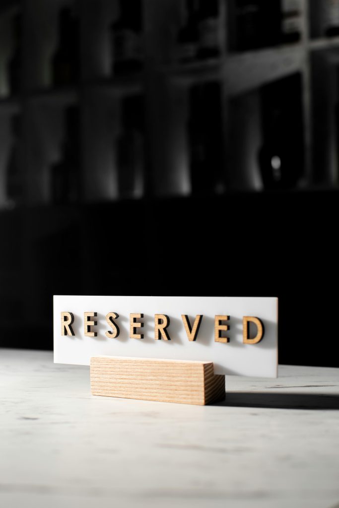 A 'Reserved' sign on a table in a stylish, dimly lit restaurant interior.